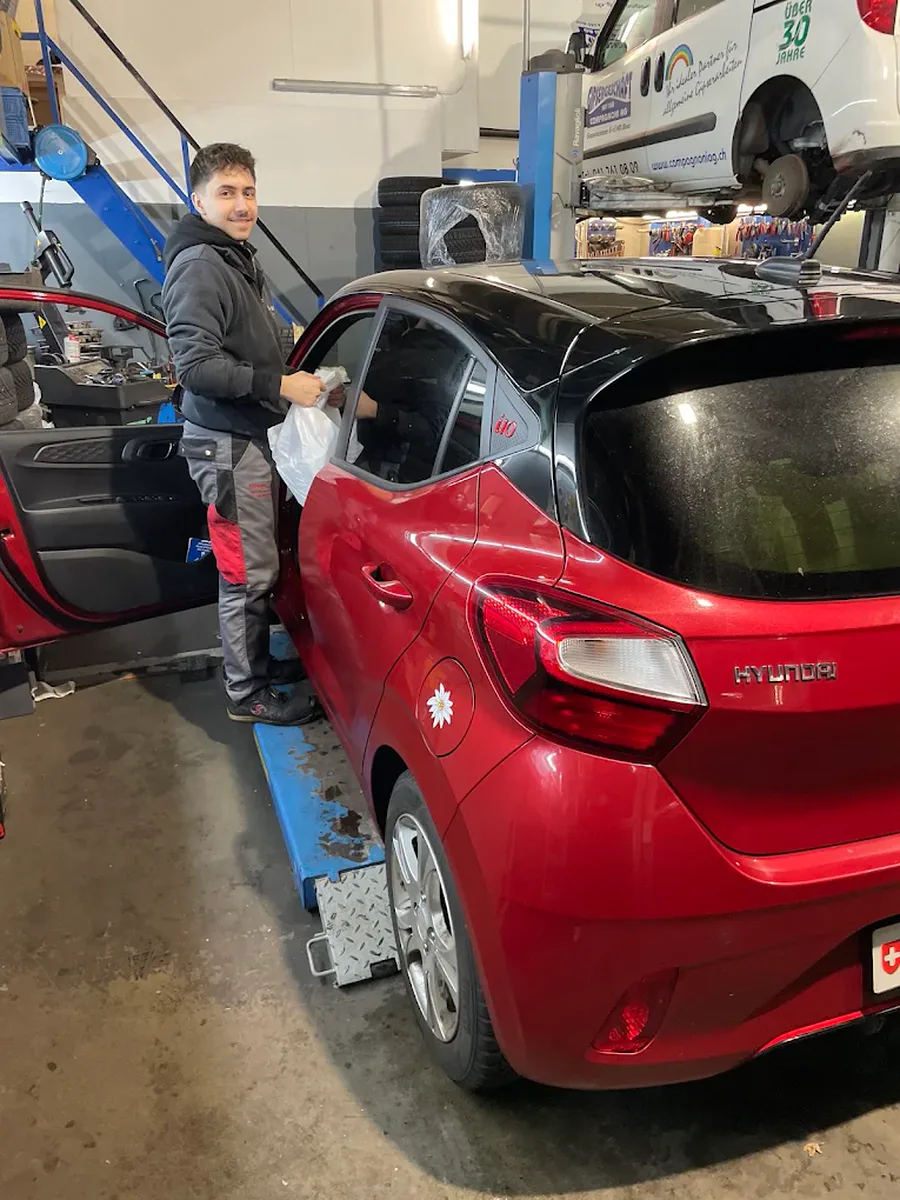 Mitarbeiter der Garage Europa neben einem Auto auf der Hebebühne